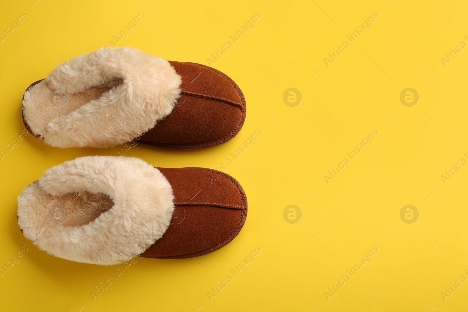 Photo of Pair of stylish soft slippers on yellow background, flat lay. Space for text