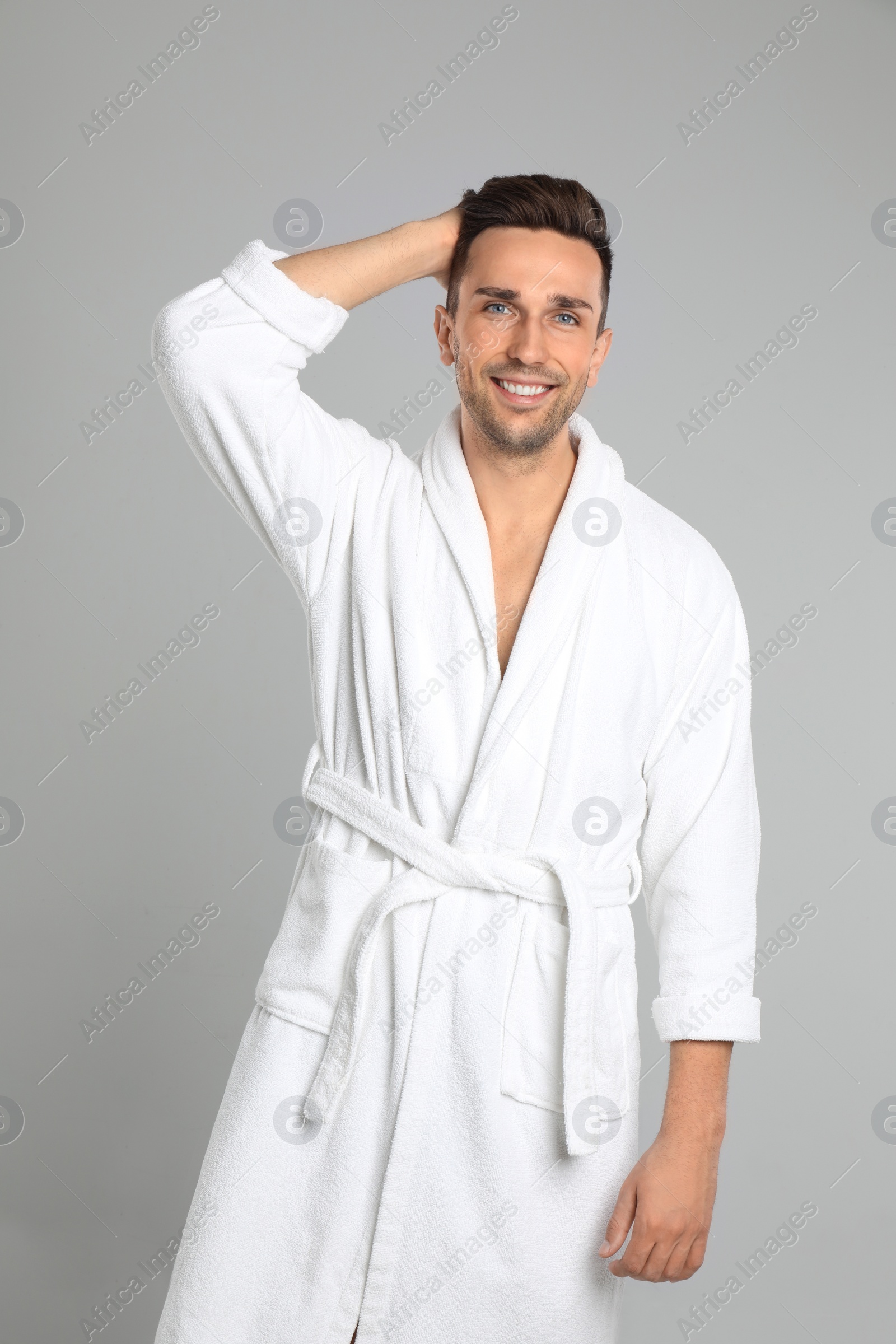 Photo of Happy young man in bathrobe on light grey background