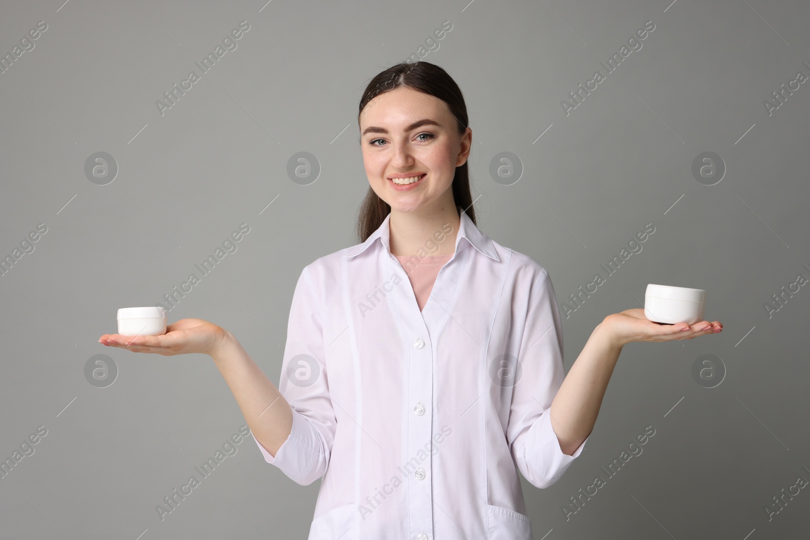 Photo of Cosmetologist with cosmetic products on grey background