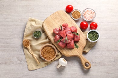 Raw beef meat and different ingredients for cooking delicious goulash on light wooden table, flat lay