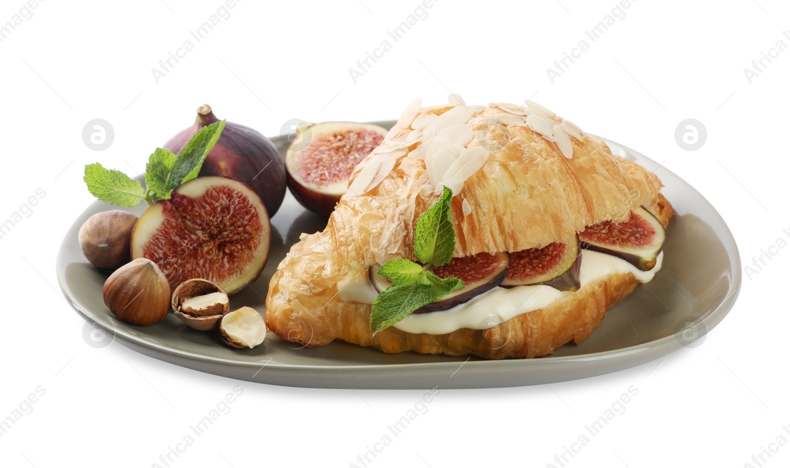 Photo of Delicious croissant with cream cheese, figs and hazelnuts isolated on white