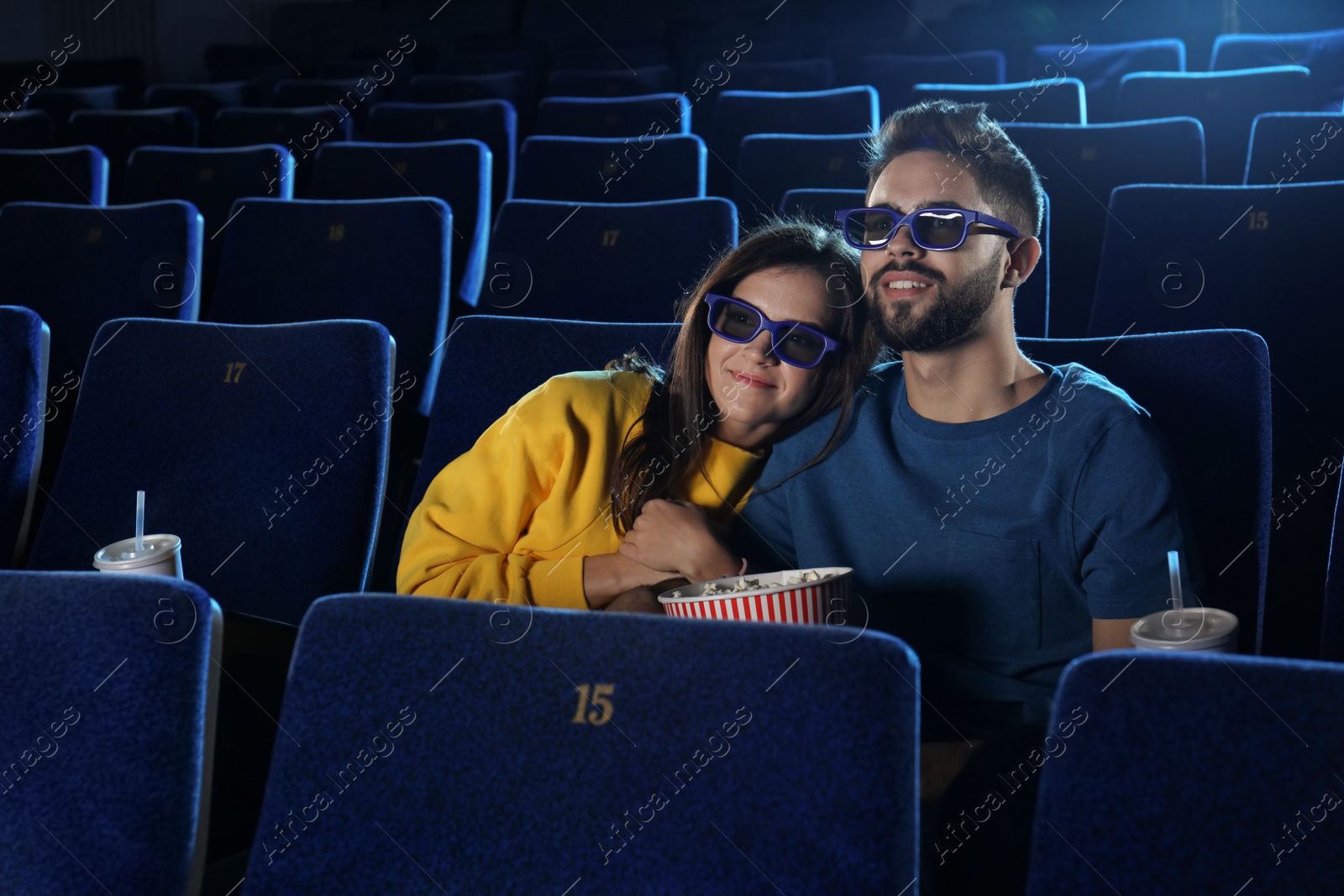 Photo of Young couple with popcorn watching movie in cinema theatre