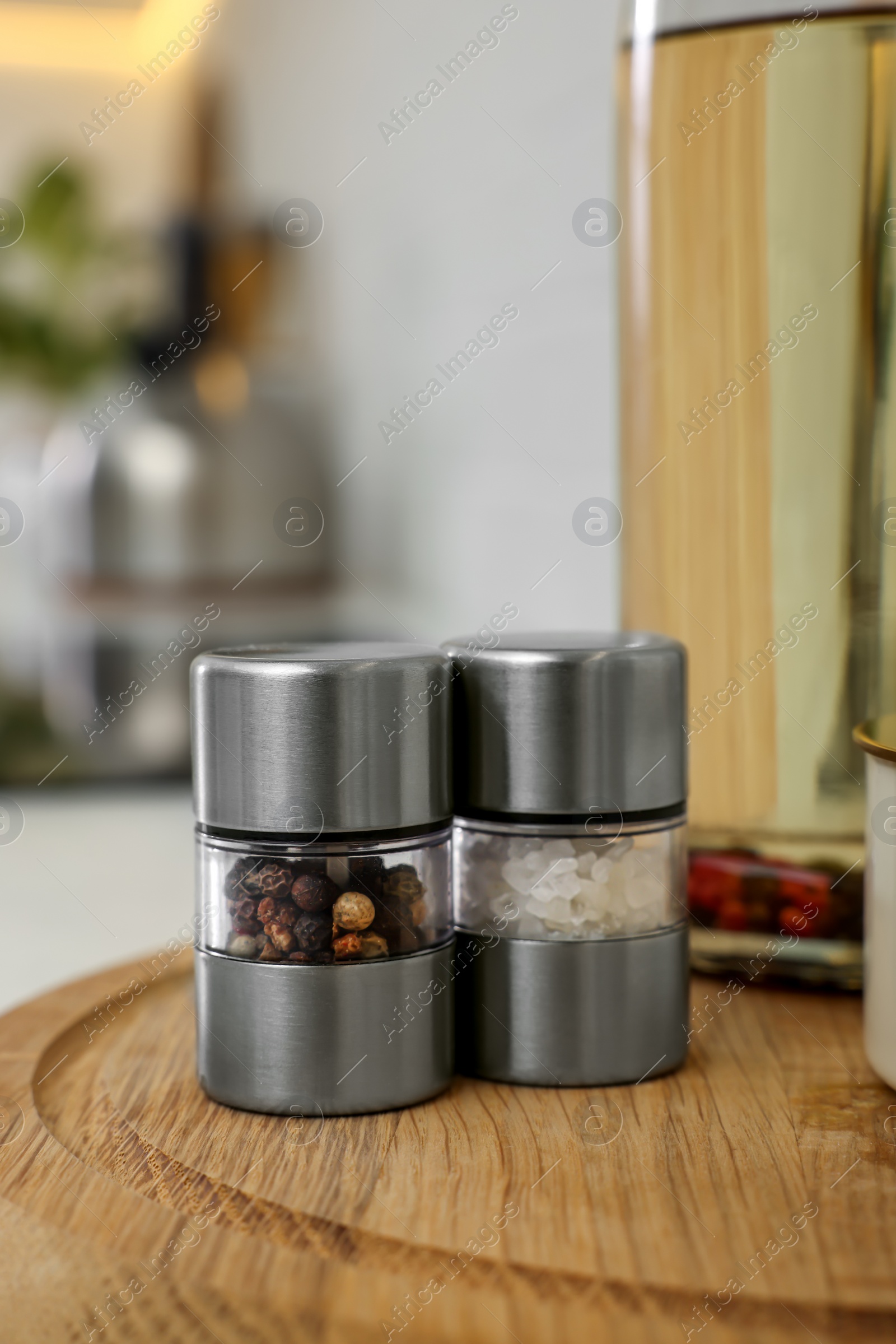 Photo of Salt and pepper mills on wooden board in kitchen. Space for text