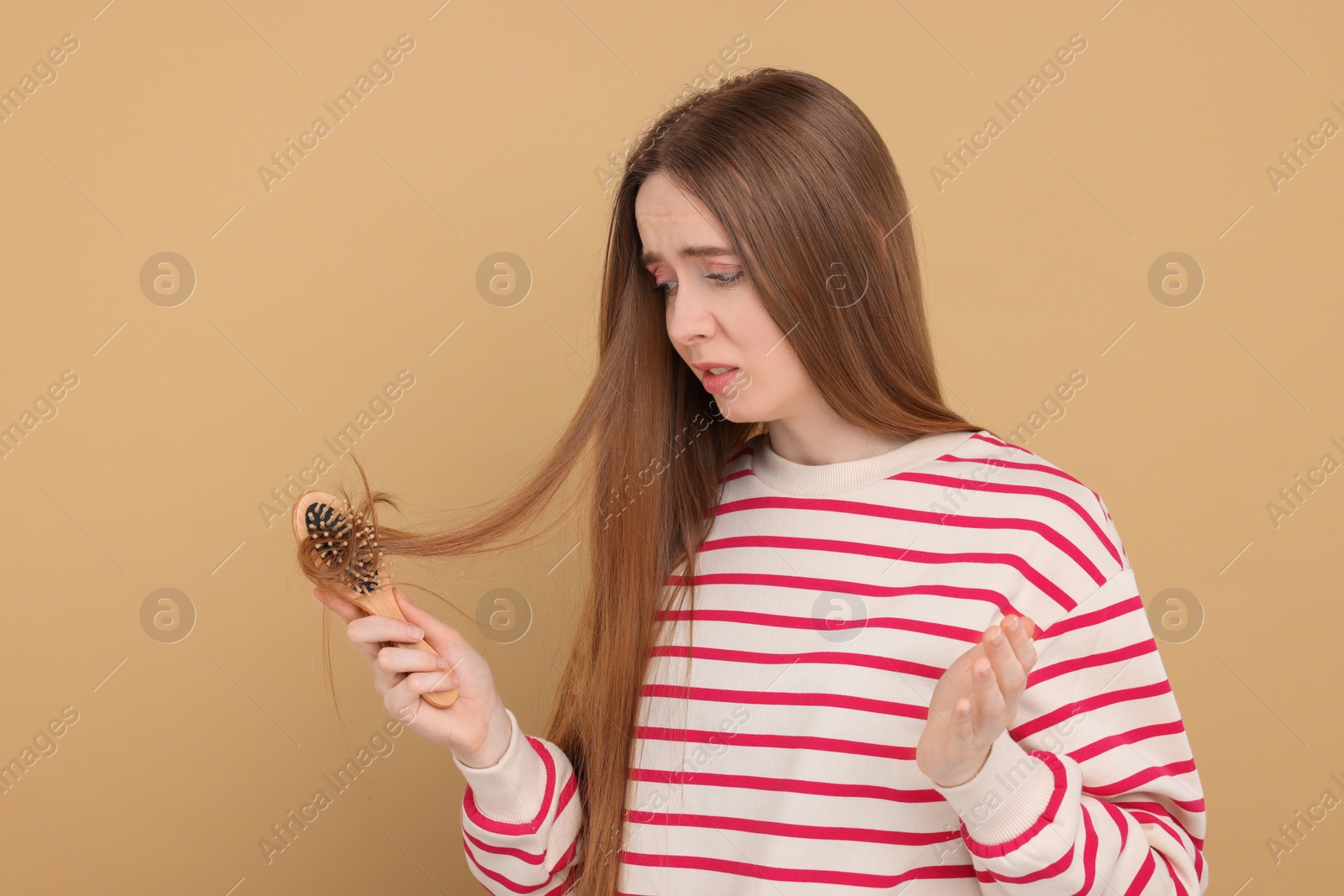 Photo of Upset woman brushing her hair on beige background. Alopecia problem