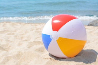 Photo of Wet colorful beach ball at seaside on sunny day, space for text