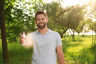 Photo of Man with insect repellent spray in park. Tick bites prevention
