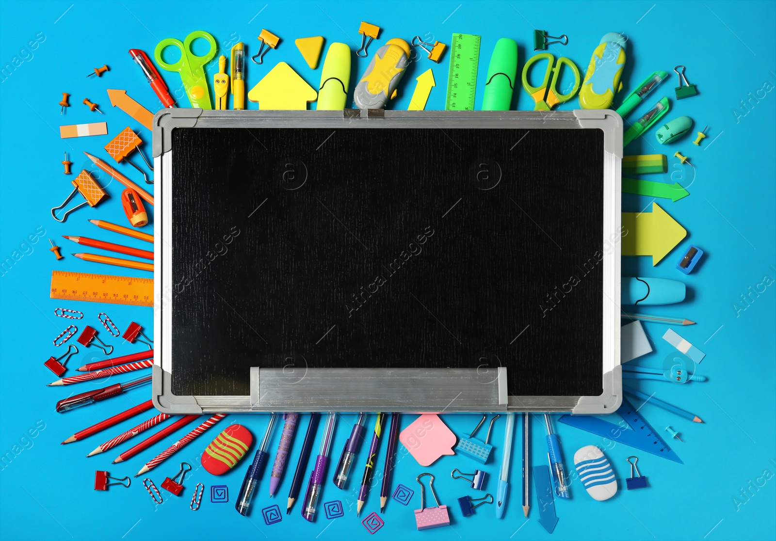 Photo of Flat lay composition with different school stationery and small chalkboard on color background