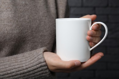 Photo of Woman holding white mug on gray background, closeup. Mockup for design