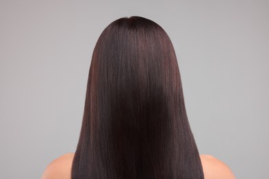 Photo of Woman with healthy hair on grey background, back view