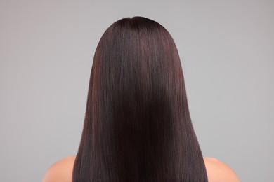 Woman with healthy hair on grey background, back view