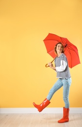 Woman with red umbrella near color wall