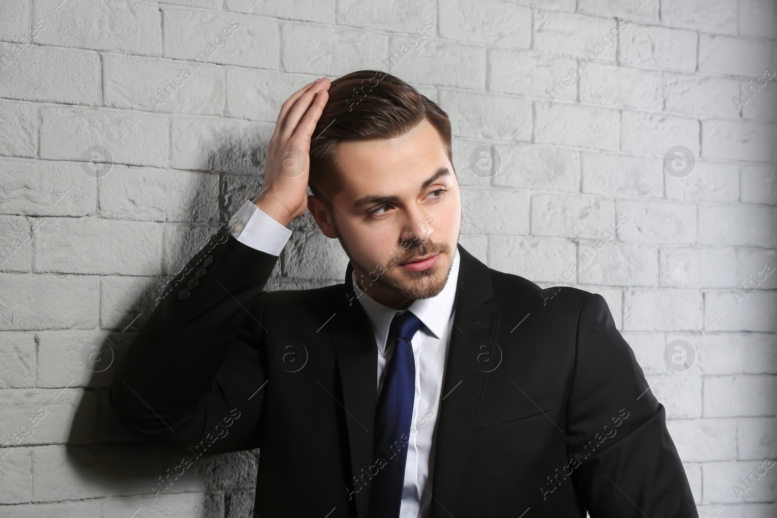 Photo of Portrait of young man with beautiful hair on brick wall background