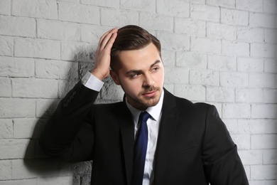 Photo of Portrait of young man with beautiful hair on brick wall background