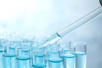 Photo of Dropping sample into test tube with light blue liquid, closeup