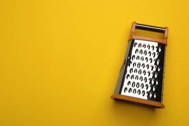 Photo of Modern grater on yellow background, top view. Space for text