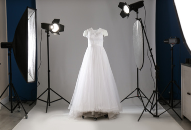 Beautiful clothes on ghost mannequin and professional lighting equipment in modern studio. Fashion photography