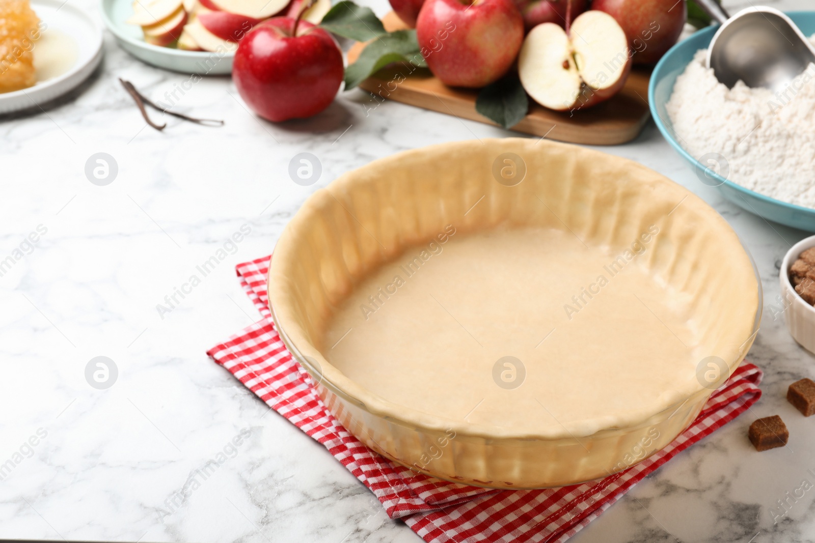 Photo of Raw dough and ingredients on white marble table, space for text. Baking apple pie