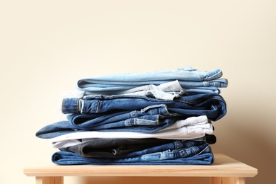 Photo of Stack of different jeans on table against color background