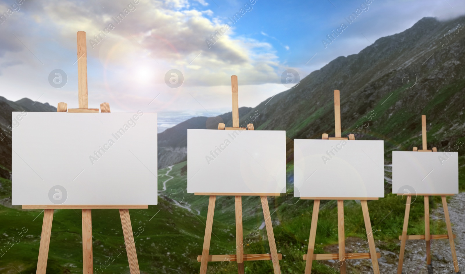 Image of Wooden easels with blank canvases in mountains on sunny day 