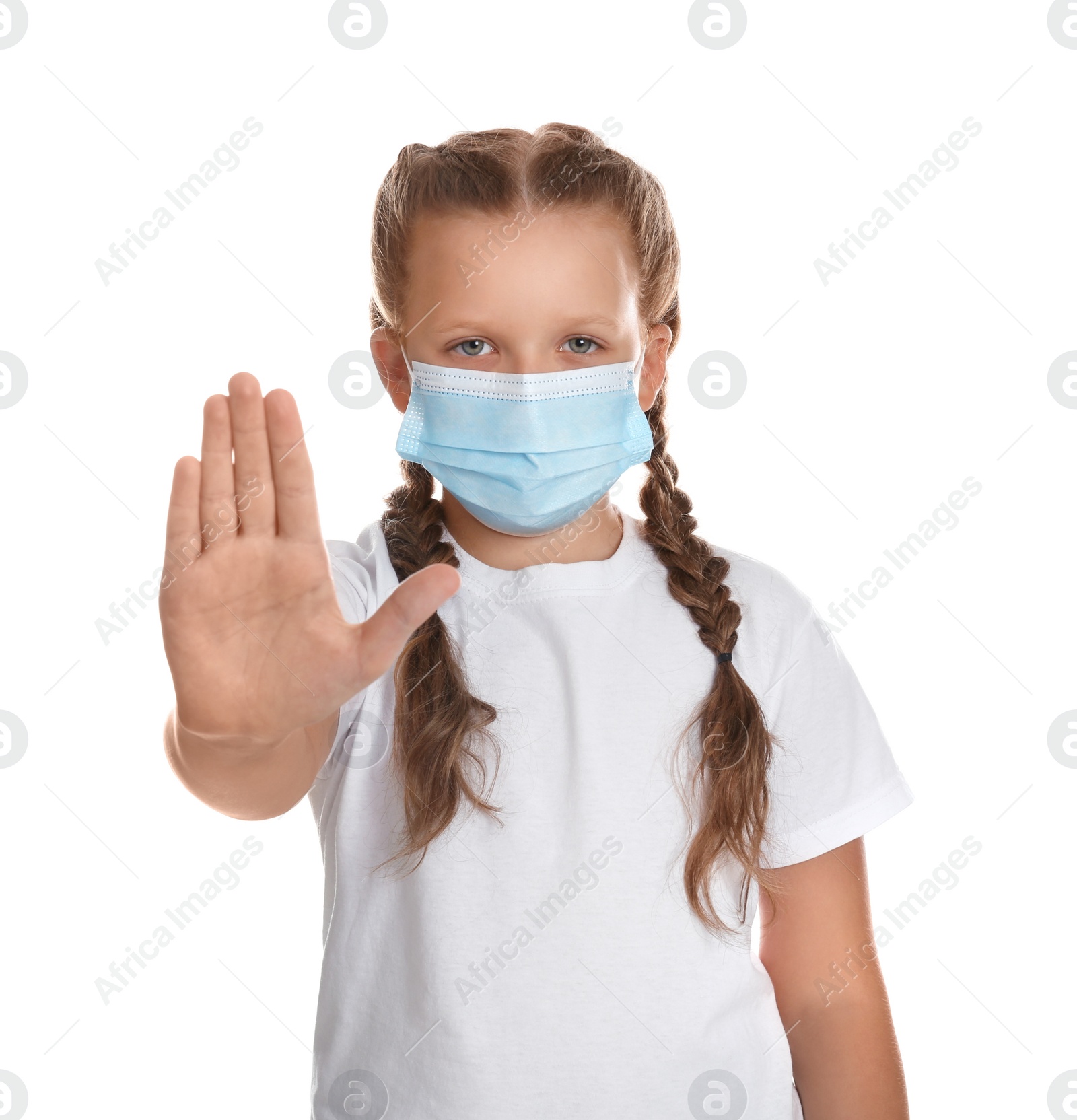 Photo of Little girl in protective mask showing stop gesture on white background. Prevent spreading of coronavirus