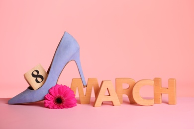 Photo of Composition with high heeled shoe and flower on table against color background, space for text. International Women's Day