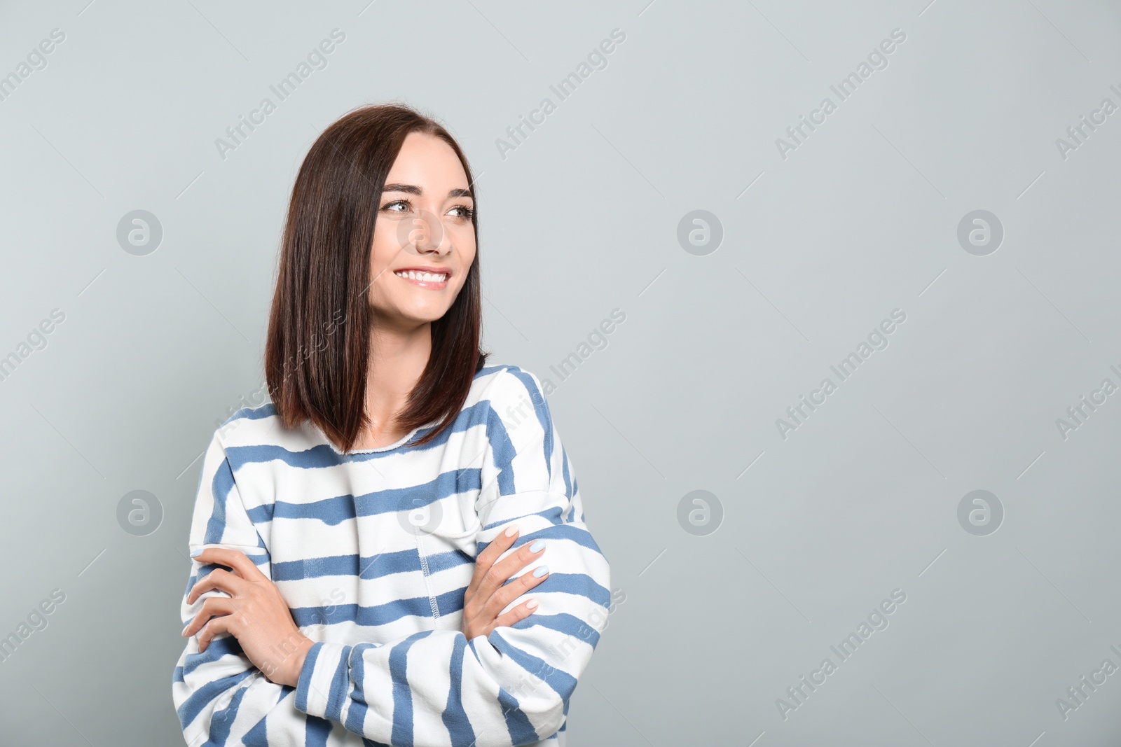 Photo of Portrait of pretty young woman with gorgeous chestnut hair and charming smile on light grey background, space for text