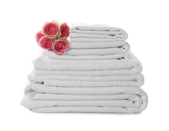 Stack of towels and bed sheets with roses on white background