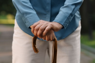 Photo of Senior woman with walking cane outdoors, closeup
