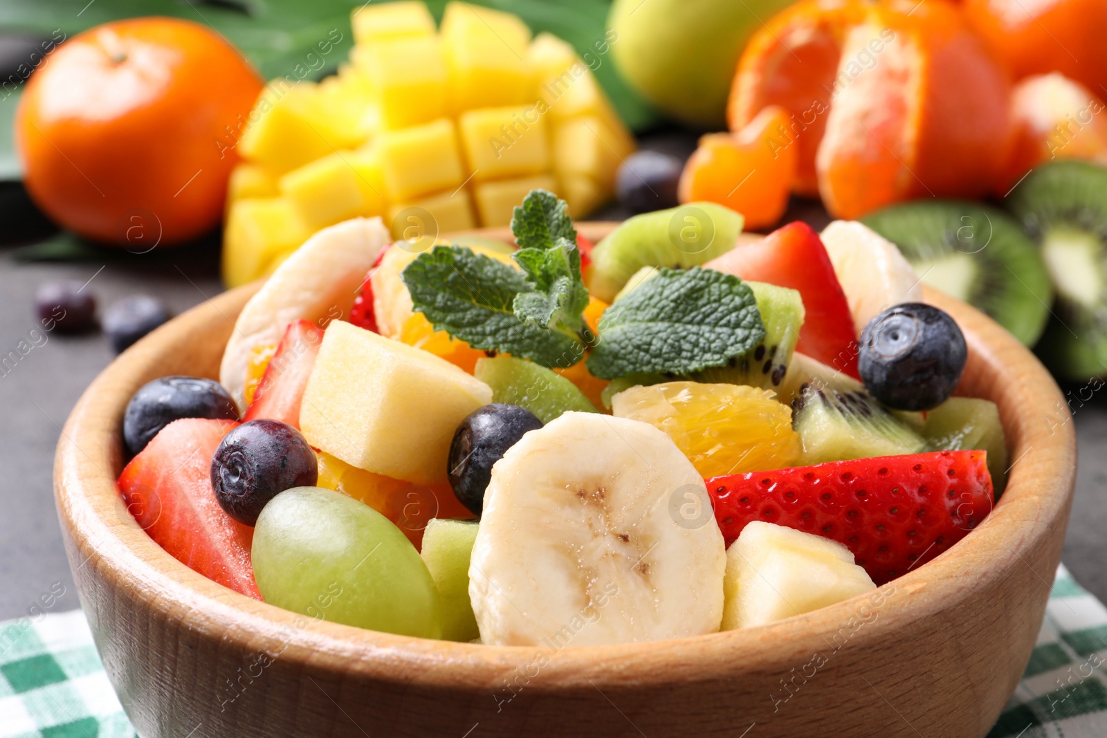 Photo of Delicious fresh fruit salad in bowl on table, closeup