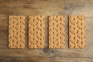 Photo of Fresh rye crispbreads on wooden table, flat lay