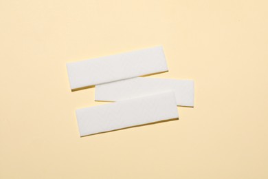 Sticks of tasty chewing gum on beige background, flat lay