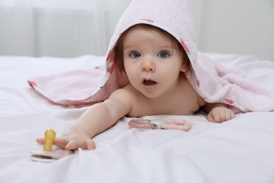 Photo of Cute little baby in hooded towel after bathing on bed at home