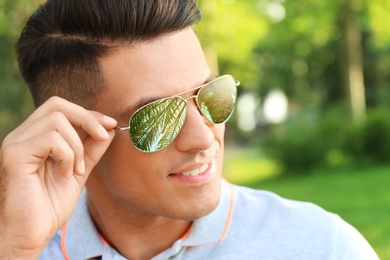 Image of Happy man on vacation. Tropical palm with green leaves reflecting in his sunglasses