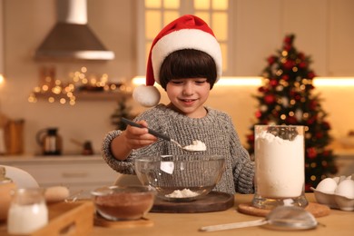 Cute little boy making Christmas cookies in kitchen