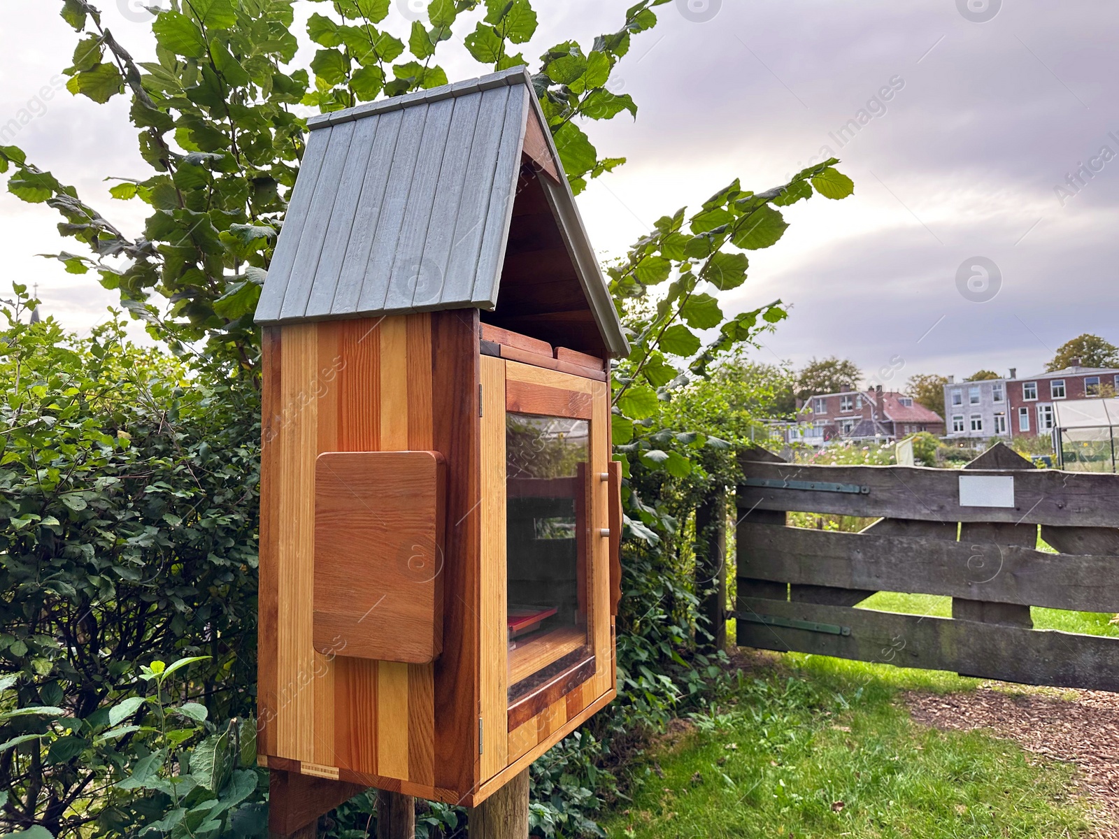 Photo of Wooden book box with signboard in Dutch language outdoors. Free library