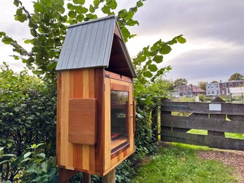 Photo of Wooden book box with signboard in Dutch language outdoors. Free library