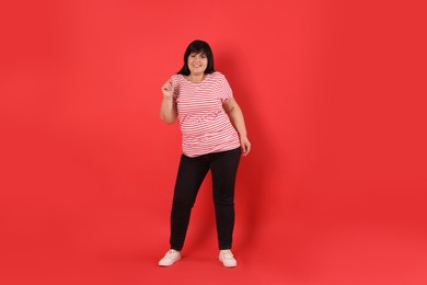 Photo of Beautiful overweight mature woman on red background