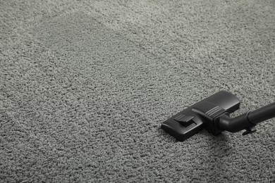 Removing dirt from grey carpet with modern vacuum cleaner. Space for text