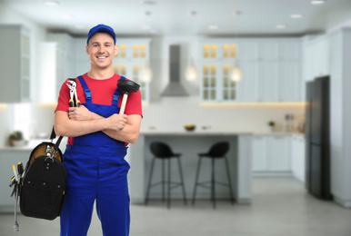 Image of Young plumber with tool bag in kitchen, space for text