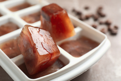 Ice cube tray with frozen coffee on grey table, closeup