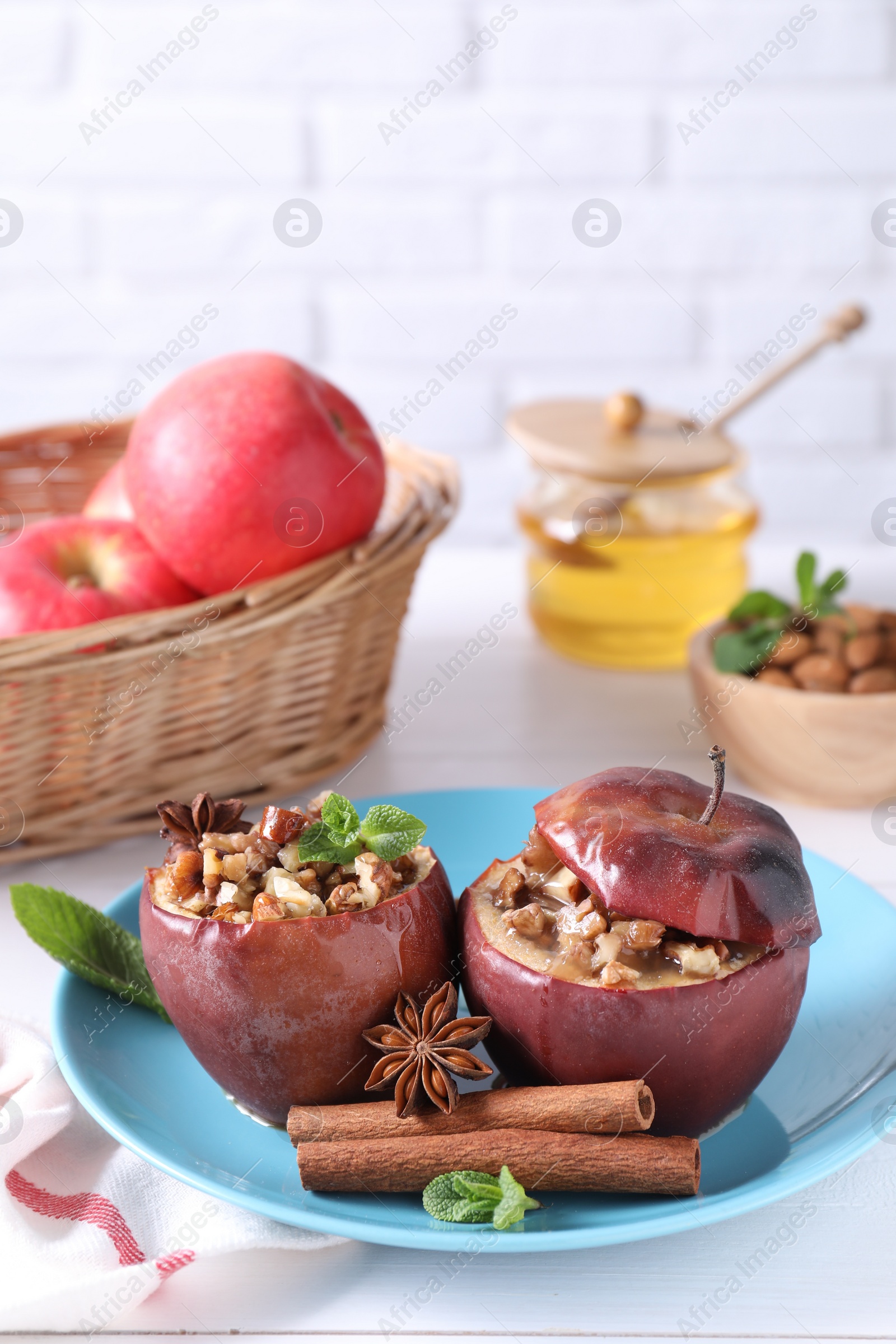 Photo of Tasty baked apples with nuts, honey, spices and mint on white wooden table