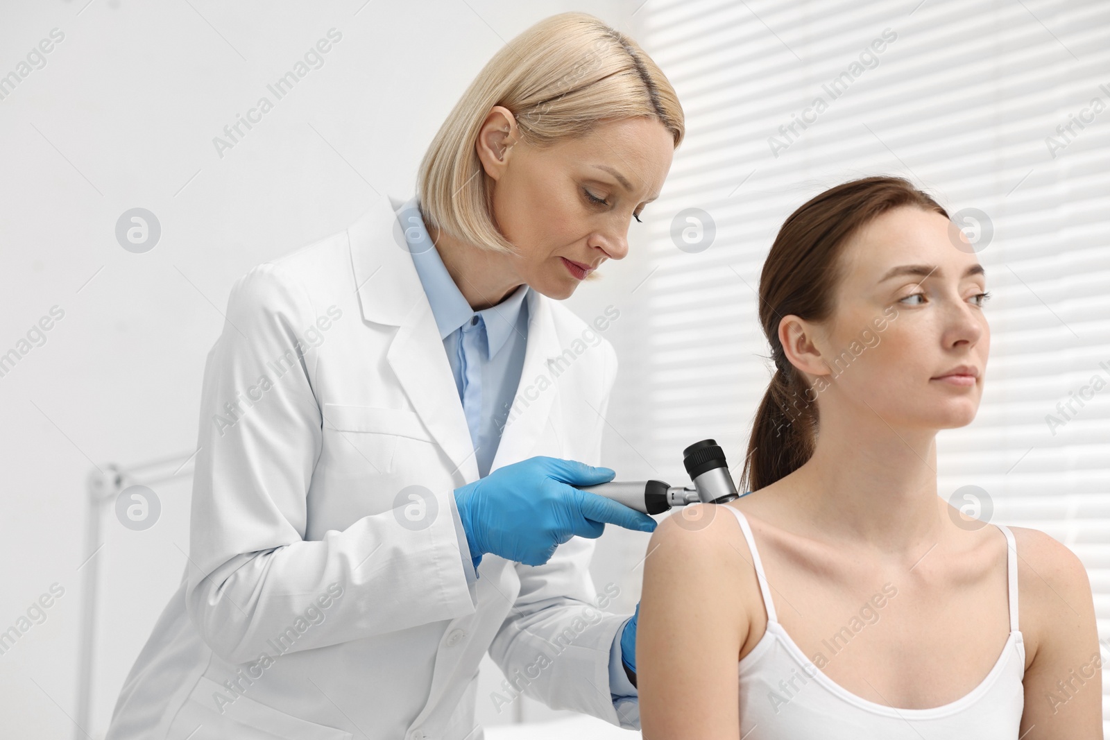 Photo of Dermatologist with dermatoscope examining patient in clinic