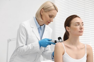 Dermatologist with dermatoscope examining patient in clinic