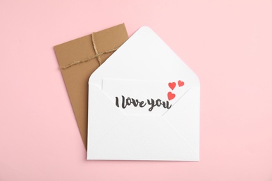 Love letter and envelope on pink background, flat lay