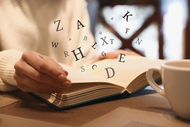 Image of Woman with coffee reading book with letters flying over it at wooden table, closeup