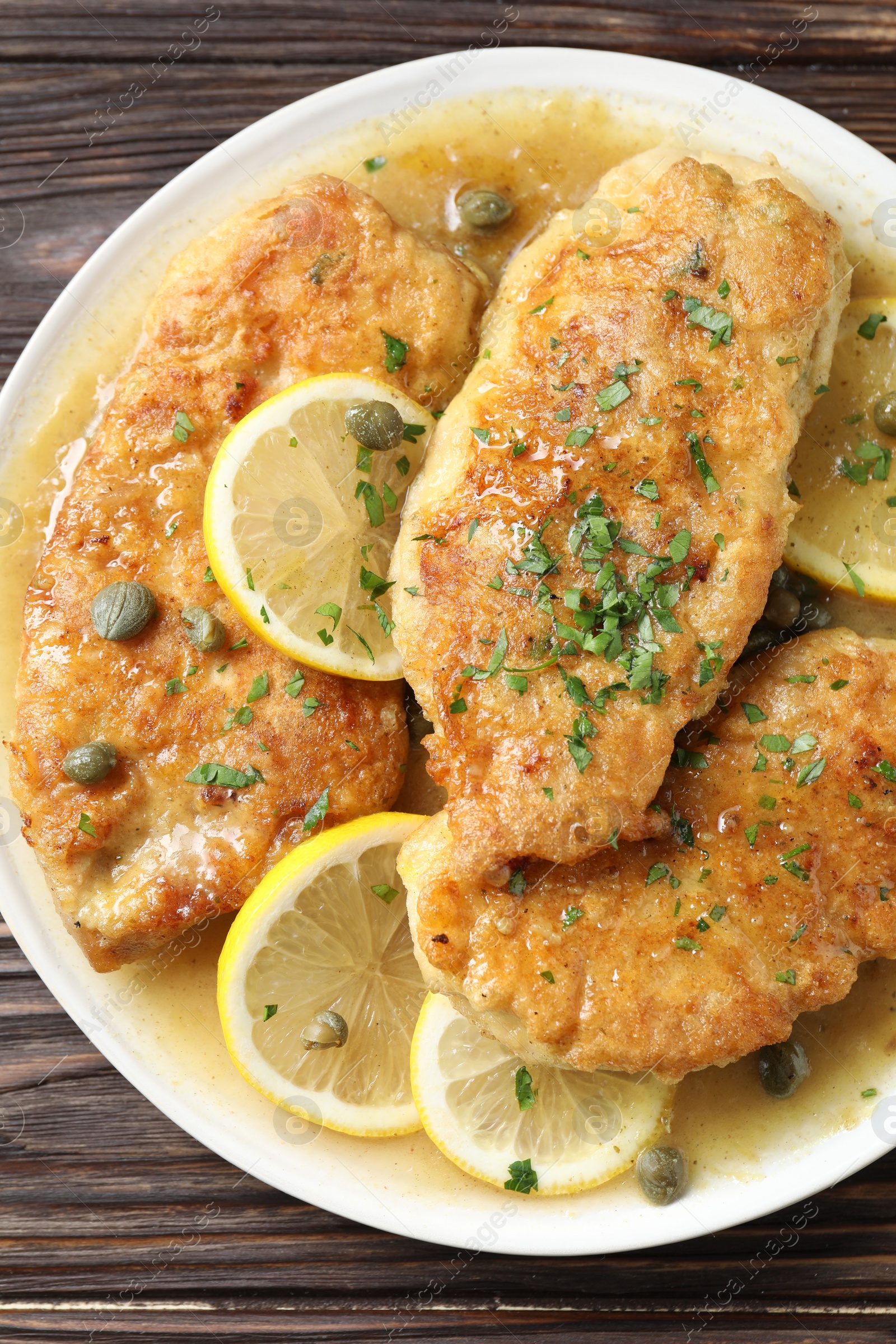 Photo of Delicious chicken piccata on wooden table, top view