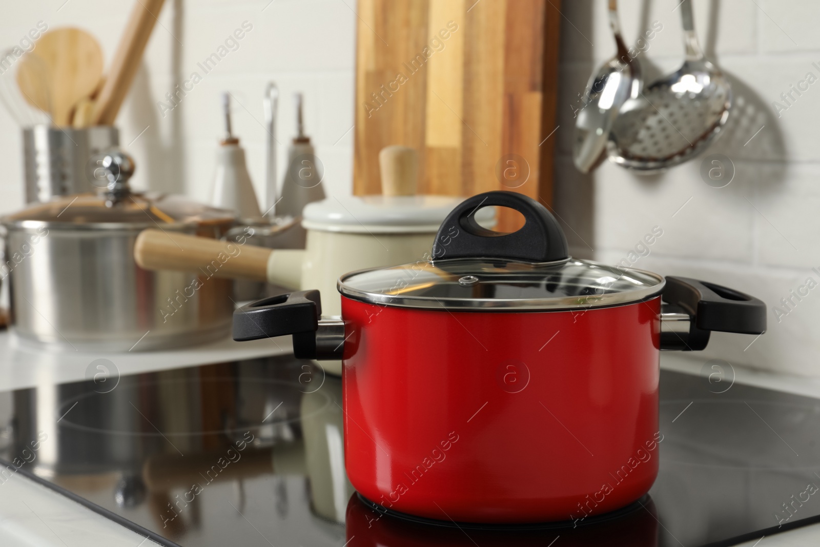 Photo of Red pot on electric stove in kitchen. Cooking utensil