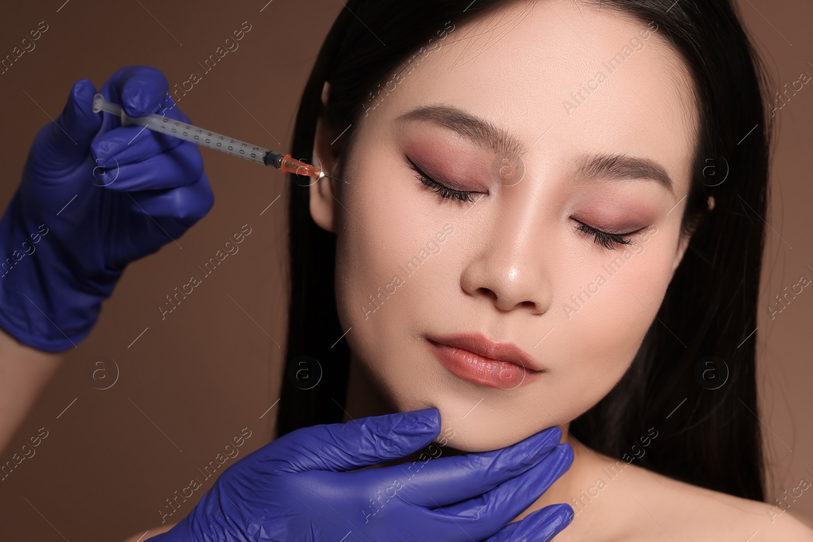 Photo of Woman getting facial injection on brown background