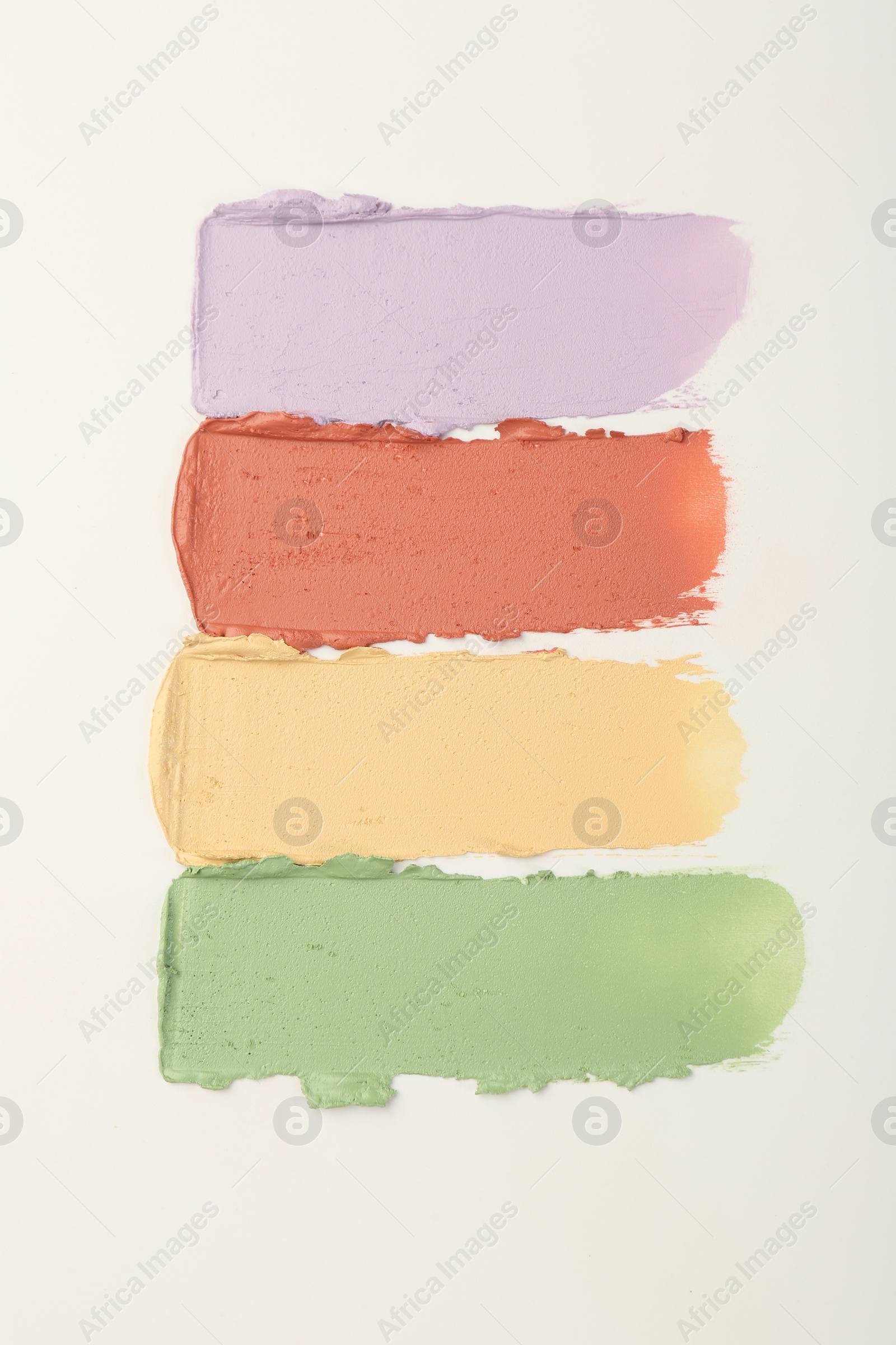 Photo of Samples of different color correcting concealers on white background, top view