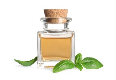 Photo of Glass bottle of basil essential oil and leaves on white background